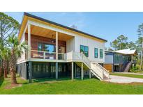 Modern home with unique architecture, featuring elevated design, wood accents, and a lush green lawn at 1012 E Erie Ave, Folly Beach, SC 29439