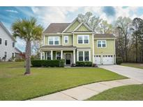 Charming two-story home features a manicured lawn, attached two-car garage, and a beautiful palm tree in the front yard at 136 Stagecoach Ln, Summerville, SC 29483