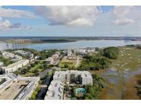 Stunning aerial view of community with waterfront, marsh views and a bridge in the background on a partially cloudy day at 145 Pier View St # 407, Charleston, SC 29492
