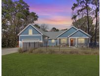 Charming blue home with a red door, black fence, and a well-manicured lawn under a lovely sunset at 1543 Scott Hill Rd, James Island, SC 29412