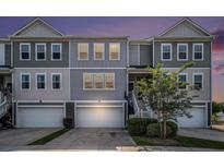 Charming gray townhome with well-maintained lawn and attached garage at dusk at 185 Winding River Dr, Johns Island, SC 29455