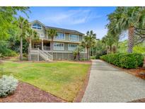 Charming two-story home with landscaped yard, palm trees, and a long driveway leading up to the property at 22 Beachwood East, Isle of Palms, SC 29451