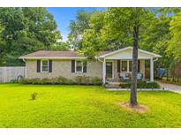 Charming brick home featuring a lush green lawn and inviting front porch with seating at 230 Azalea Ct, Moncks Corner, SC 29461