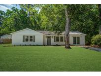 Charming one-story home with lush lawn, mature trees, and inviting painted brick facade at 3231 Stonehaven Dr, North Charleston, SC 29420
