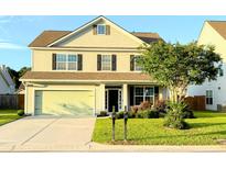 Well-maintained two-story home with lush landscaping, an attached garage, and a sunny front yard at 332 Southern Sugar Ave, Moncks Corner, SC 29461