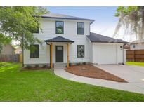 Beautifully renovated two-story home featuring a manicured lawn and a private driveway leading to an attached garage at 397 Parkdale Dr, Charleston, SC 29414