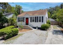 Charming home with a red door, black shutters, well-maintained landscaping, and a gravel driveway at 4932 N Rhett Ave, North Charleston, SC 29405