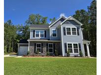 Charming two-story home with stone accents, black shutters, attached garage, and lush green lawn at 6121 Sourwood Trl, Ridgeville, SC 29472
