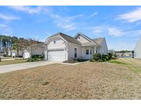 Charming white home featuring an attached two-car garage, manicured landscaping and partial view of a lake at 109 Billowing Sails St, Summerville, SC 29486