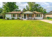 Charming white brick home with a well-manicured lawn, rocking chairs, and lovely landscaping at 114 Bailey Dr, Summerville, SC 29485