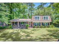 Charming brick home with lush green lawn and mature trees offers inviting curb appeal at 123 Azalea Dr, Summerville, SC 29485