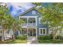 Charming blue two-story home boasts a welcoming porch and beautifully landscaped front yard on a sunny day at 1588 Paradise Lake Dr, Mount Pleasant, SC 29464