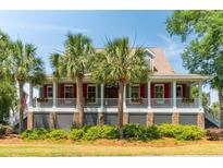 Charming home featuring a spacious front porch, brick foundation, and beautiful palm trees at 16 Fairway Village Ln, Isle of Palms, SC 29451