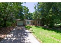 Charming brick home features an attached garage, driveway, and a lush green lawn with mature trees providing ample shade at 210 Froman Dr, Summerville, SC 29483
