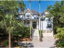 Charming two-story home features a well-manicured lawn, a two-car garage, and plentiful trees offering shade and privacy at 24 Beachwood West, Isle of Palms, SC 29451