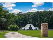 Charming white barn-style home with lush green lawn and mature trees on a sprawling property at 2470 Breakaway Trl, Johns Island, SC 29455