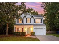 Charming two-story home with white siding, black shutters, a cozy front porch, and manicured landscaping at 334 Mossy Oak Way, Mount Pleasant, SC 29464