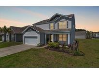 Charming two-story home featuring a manicured lawn and attached two-car garage at 411 Bering Ln, Summerville, SC 29486