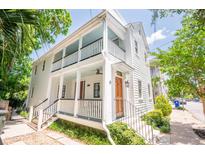 Inviting two-story home featuring a double porch, white siding, manicured landscaping, and natural light at 50 South St, Charleston, SC 29403