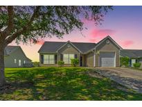 Charming single-story home featuring a well-manicured lawn and inviting curb appeal at sunset at 5042 Thornton Dr, Summerville, SC 29485