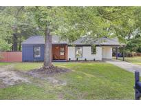 Charming single-story home featuring a cozy front porch, a covered carport, and a well-maintained lawn at 7674 Chippendale Rd, North Charleston, SC 29420