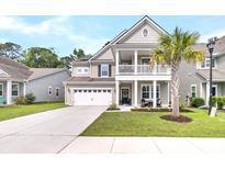 Charming two-story home features a front porch, attached garage, and a well-manicured lawn with a palm tree at 9829 English Elm St, Ladson, SC 29456