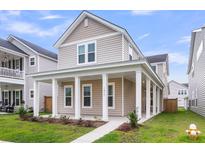 Charming two-story home featuring a welcoming front porch with stately white columns and a well-manicured lawn at 1017 Marsh Royal St, Summerville, SC 29485