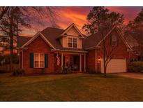 Charming two-story brick home with a well-manicured lawn and inviting front porch at dusk at 106 Sago Palm Ct, Summerville, SC 29483