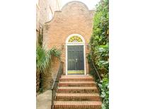 Charming brick building with a black front door and a brick stairway, surrounded by lush greenery at 12 Bee St # C, Charleston, SC 29403
