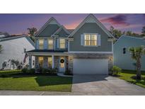 Charming two-story home boasts a mix of stone and siding, enhanced by a lush green lawn and twilight sky at 121 Cherry Grove, Summerville, SC 29483