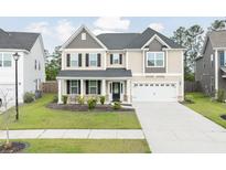 Charming two-story home with a manicured lawn, covered porch, and two-car garage at 283 Saxony Loop, Summerville, SC 29486