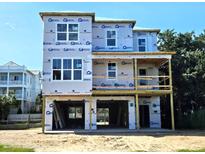 Three-story home under construction featuring a covered porch and large windows with protective building wrap visible at 312 Palm Blvd, Isle of Palms, SC 29451