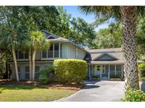 Charming two-story home with lush landscaping, mature trees, and inviting covered porch at 33 Painted Bunting Ln, Kiawah Island, SC 29455