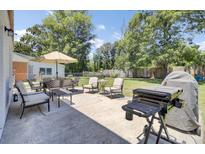 Inviting back patio with dining set, lounge chairs, grill, and spacious yard perfect for outdoor entertaining at 3428 Plaza Ln, North Charleston, SC 29420