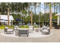 Outdoor lounge area features comfortable seating, modern fire pit, and a tranquil wooded backdrop at 708 Breakers Reef Ln, Huger, SC 29450