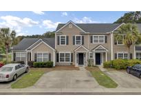 Charming townhome featuring neutral siding, black shutters, well-maintained landscaping, and a private driveway in a desirable community at 1005 Washitonia Way # B, Charleston, SC 29492
