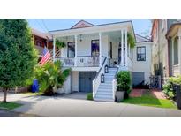 Charming home featuring a welcoming front porch, stylish stairs with lantern decor, and lush landscaping at 11 Francis St, Charleston, SC 29403