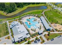 Aerial view of a community pool with several people in the pool and a view of a pond and wooded area at 112 Crimson St, Summerville, SC 29486