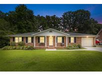 Charming single story brick home featuring a manicured front lawn and covered porch with swing at 2045 Vestry Dr, Charleston, SC 29414