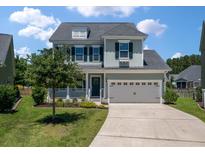 Charming two-story home with green siding, shuttered windows, a 2-car garage and manicured lawn at 214 Center Hill Ct, Summerville, SC 29485
