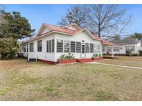 Charming exterior of white home with a vibrant red roof and manicured lawn at 222 E Main St, Moncks Corner, SC 29461