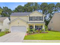 Charming two-story home with yellow siding, black shutters, well-manicured lawn and beautiful landscaping at 230 Sweet Alyssum Dr, Ladson, SC 29456