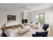 Bright living room features a fireplace, white sofas with blue pillows, and sliding glass door to the outside at 2333 Tall Sail Dr # G 607, Charleston, SC 29414