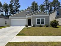 Charming single-story home with a well-manicured lawn and attached garage at 305 Camellia Bloom Dr, Moncks Corner, SC 29461