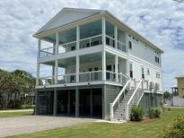 Beautiful three-story beach house with white siding and multiple covered decks for outdoor living at 305 Matilda St, Edisto Beach, SC 29438