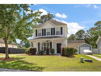 Charming two-story home with a well-manicured lawn, mature trees, and inviting front porch at 8987 Planters Row Ln, Summerville, SC 29485