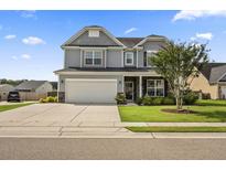 Charming two-story home with a well-manicured lawn, gray siding, and a two-car garage at 9009 Chato Ct, Summerville, SC 29483