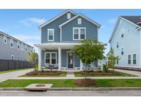 Charming two-story blue home boasts a welcoming front porch and well-manicured lawn at 238 Bird Song Path, Summerville, SC 29485