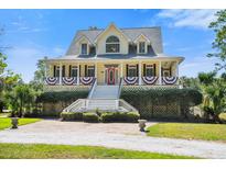 Charming home with a welcoming porch, beautiful landscaping, and a vibrant red front door at 8970 Palmetto Rd, Edisto Island, SC 29438