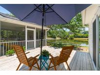 Charming back deck with wooden chairs, umbrella, and beautiful lake views, perfect for relaxation and outdoor enjoyment at 1027 Wayfarer Ln, Charleston, SC 29412